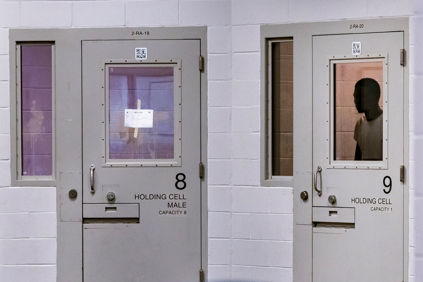 A person is detained inside a holding cell in the Harris County Joint Processing Center.