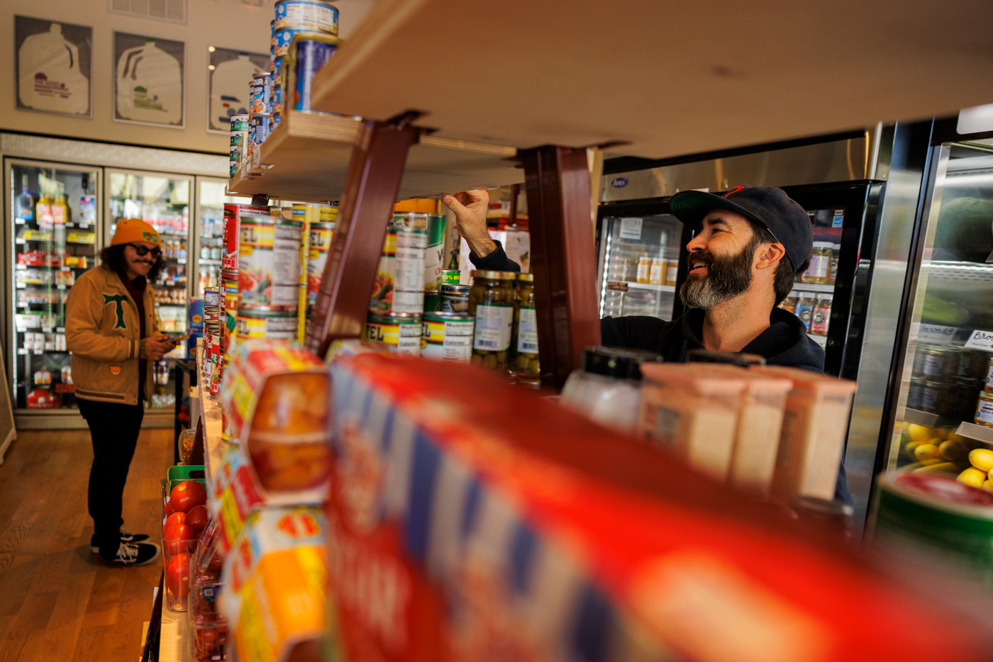 Sam Newman, right, a grocer in the East End, places products on the shelves of his Houston store.