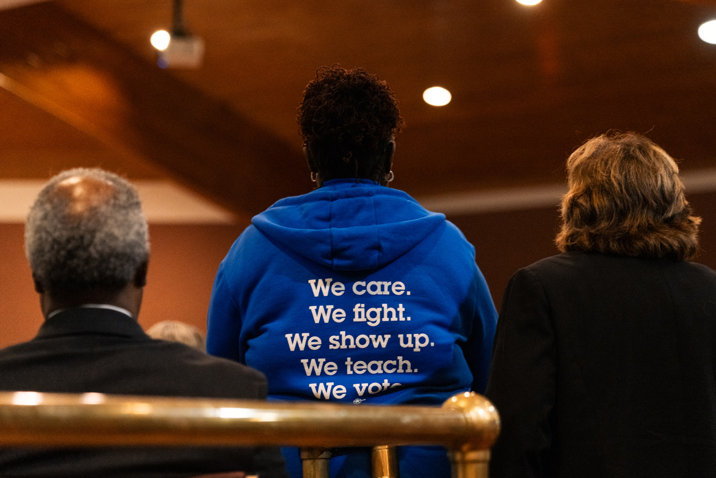 A woman’s jacket reads, “We care. We fight. We show up. We teach. We vote.”