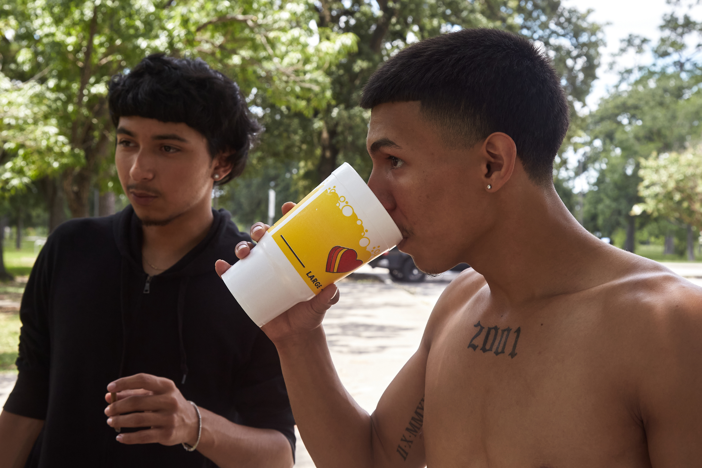 A young man drinks a beverage during a hot day