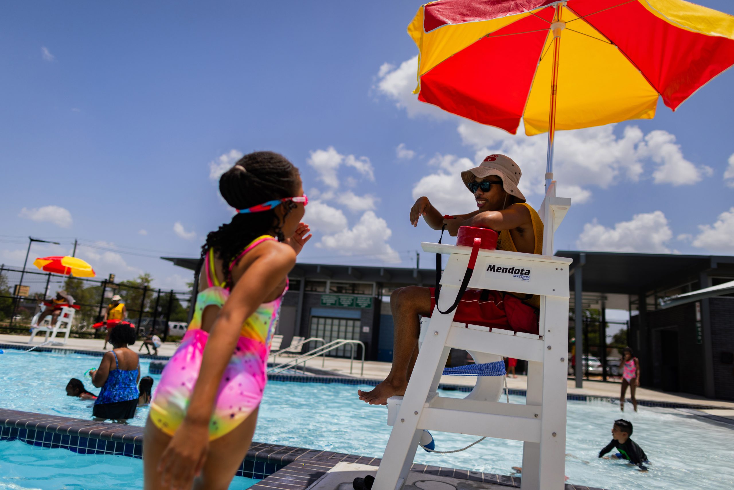 Alief Neighborhood Center and Park pool lifeguard Tariq Hamid, 16, talks to a young bather while on duty.