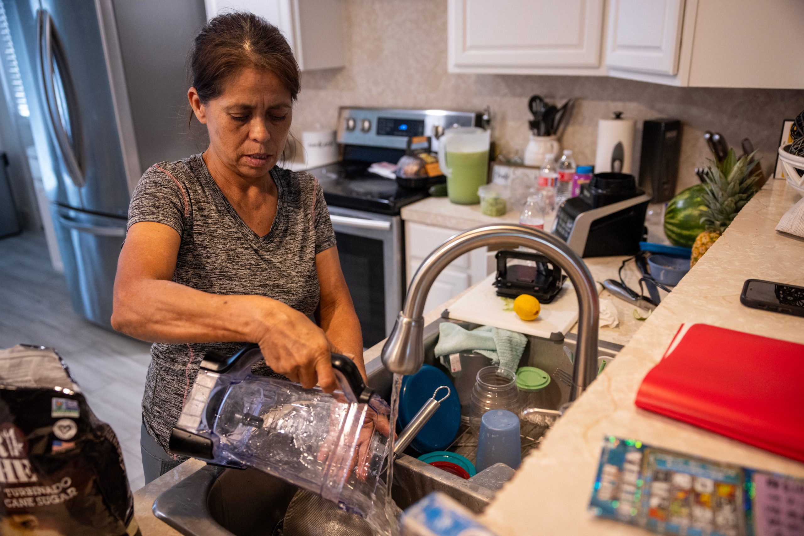 Irma Acosta washes a blender as she cooks dinner at her son’s home, in Fresno, Texas