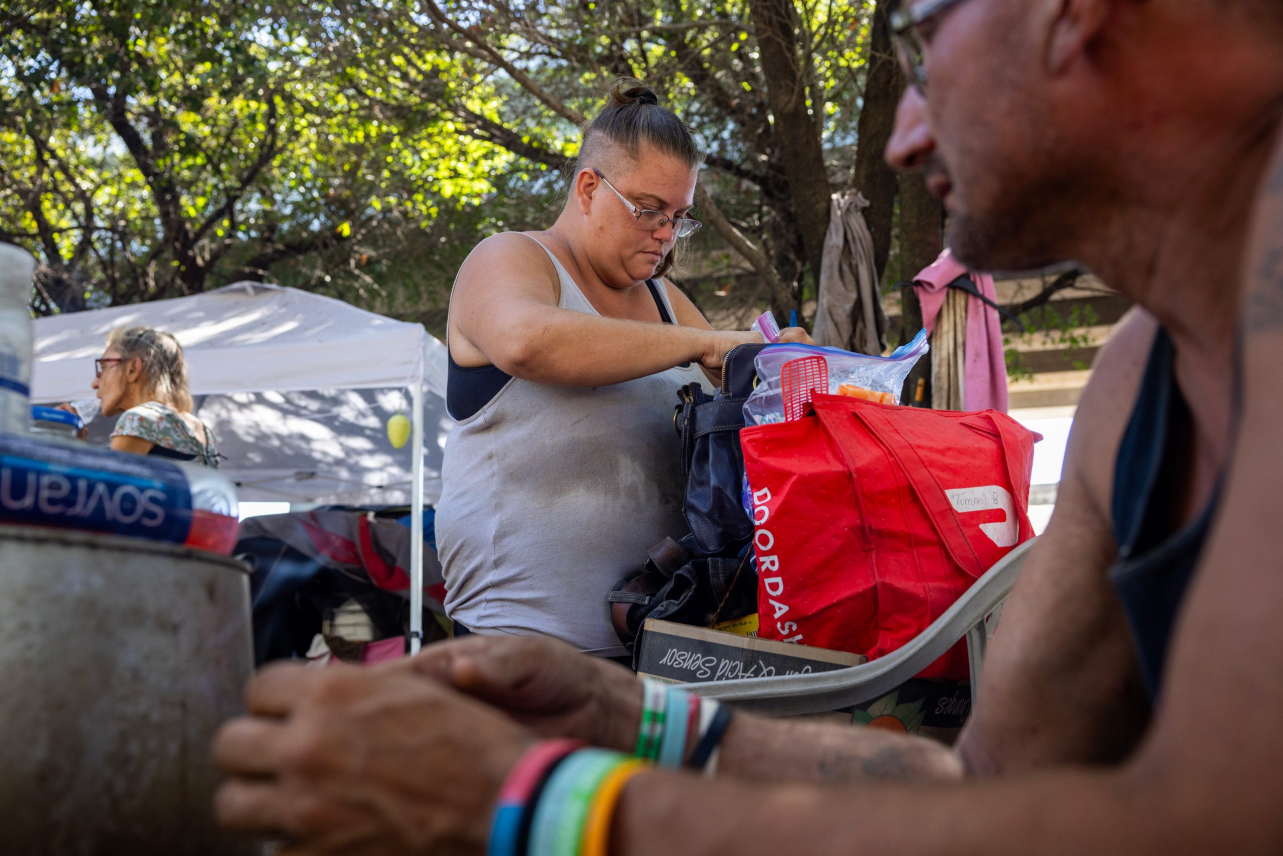 Sara Smith, at center, looks at her mail at an encampment under an overpass in Houston
