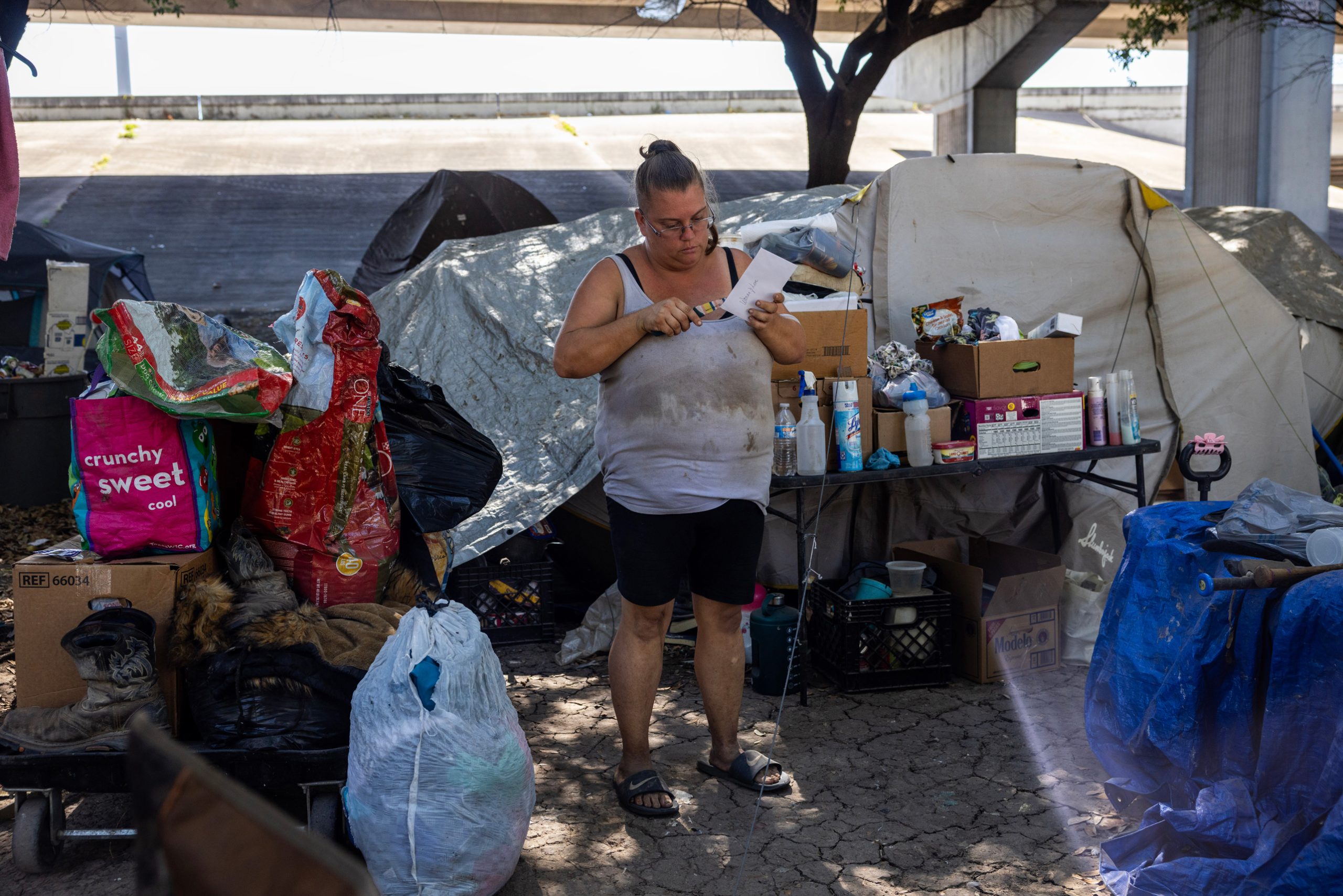 Sara Smith looks at her mail at an encampment under an overpass