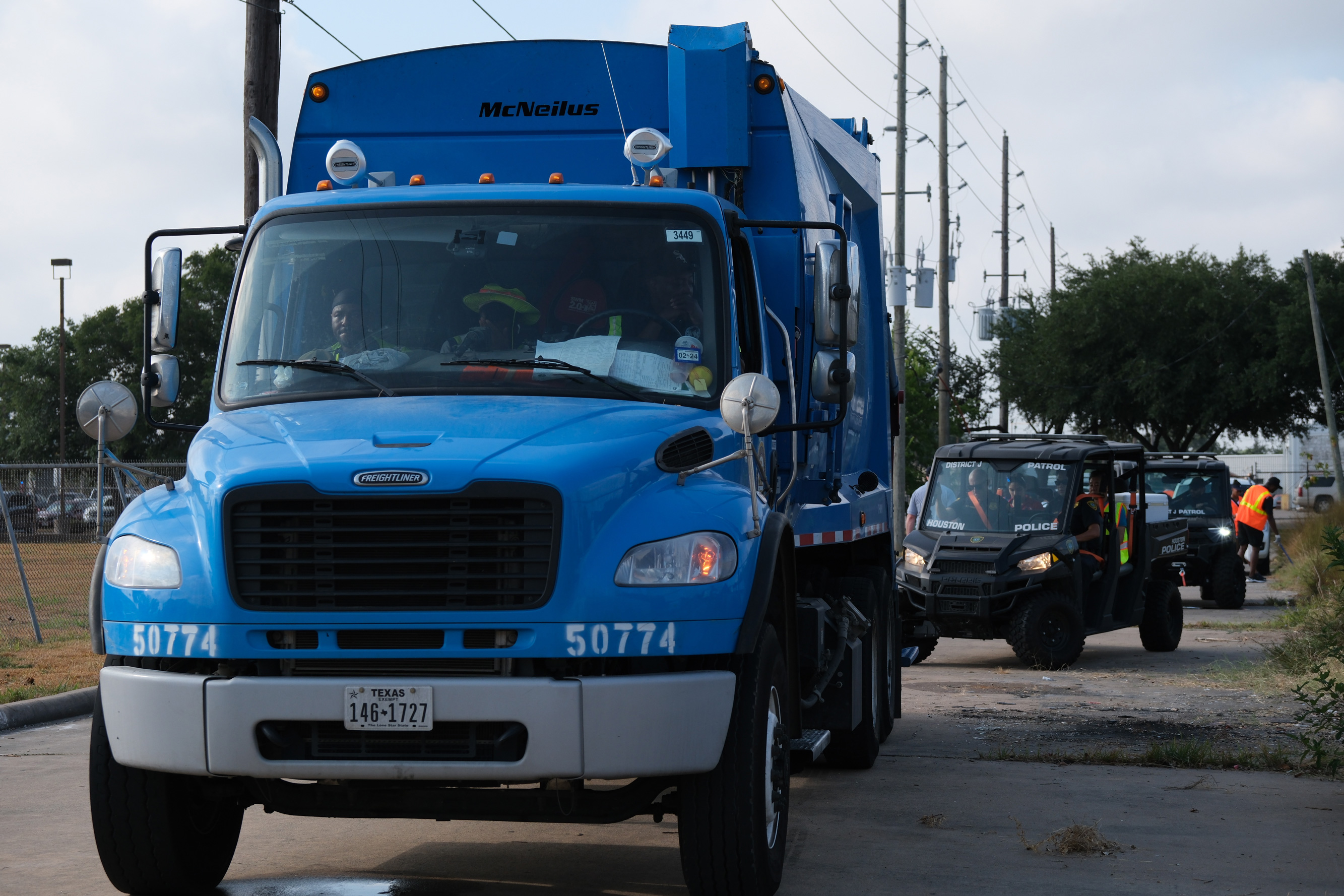 A garbage truck and Houston Police Department vehicles drive through a Bissonnet corridor during a community cleanup. 