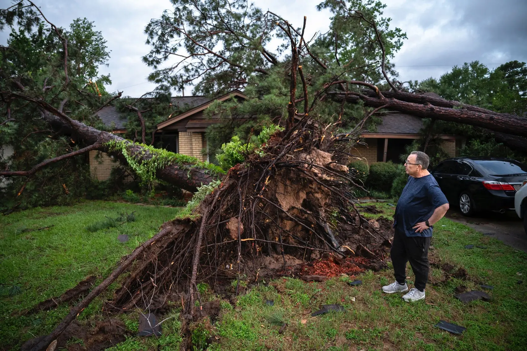 A man stands by a fallen tree after severe storms left nearly 900,000 CenterPoint Energy customers without power and killed at least four people in the Houston area