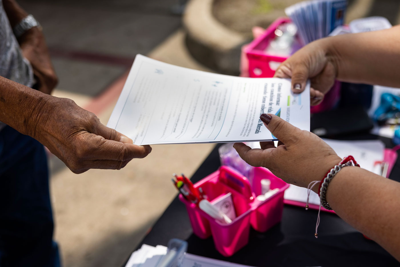 Abelardo Rodriguez, at left, takes an informational pamphlet from Margarita Romo, of Civic Heart Community Services, at right, while he asks about helping his daughter apply for Medicaid during a community health event,