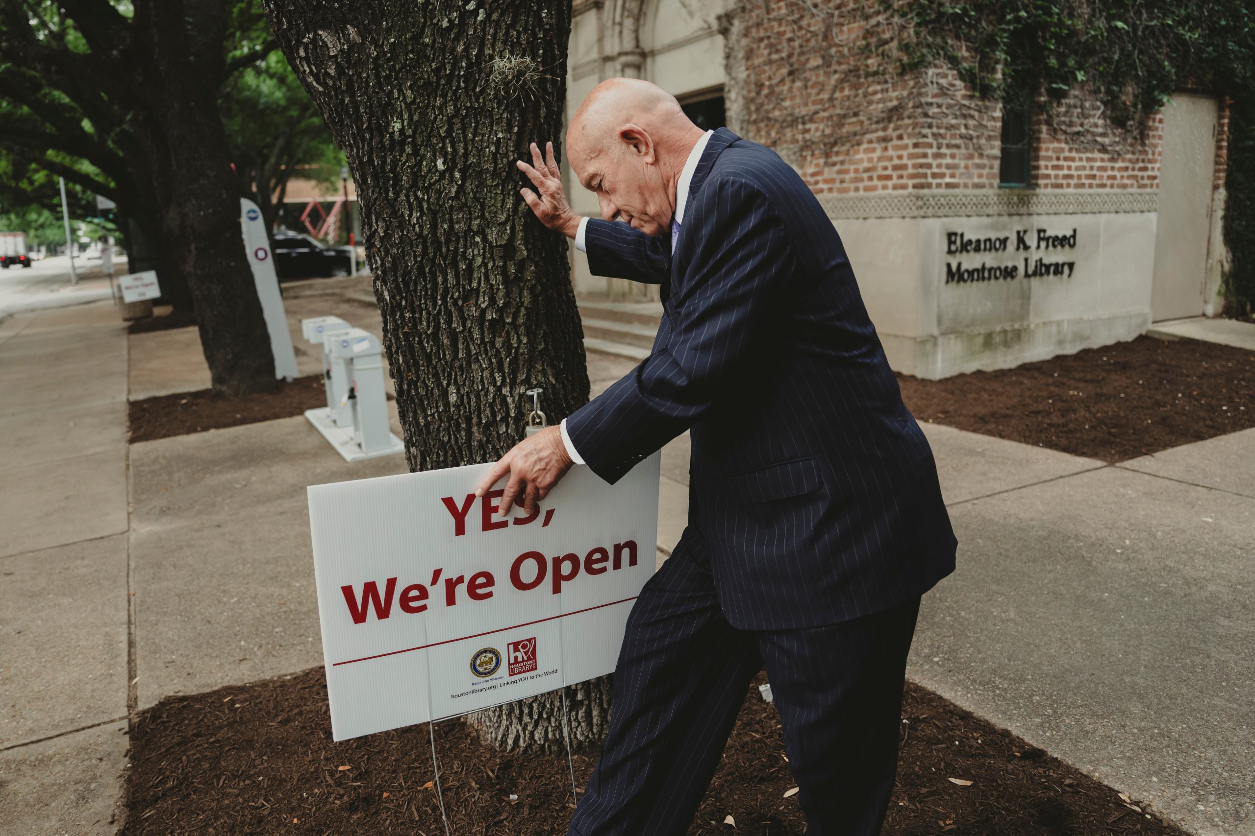 Mayor John Whitmire sticks a 'Yes, We're Open' sign infront of the Eleanor K. Freed Montrose Library on April 15, 2024 in Houston.